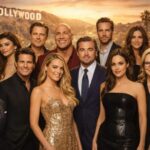 Group of famous Hollywood male and female actors posing together in elegant outfits with the Hollywood sign in the background.