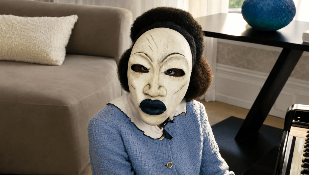 A mysterious masked figure sits beside a piano in a tense scene from Tyler Perry's psychological thriller Strung.